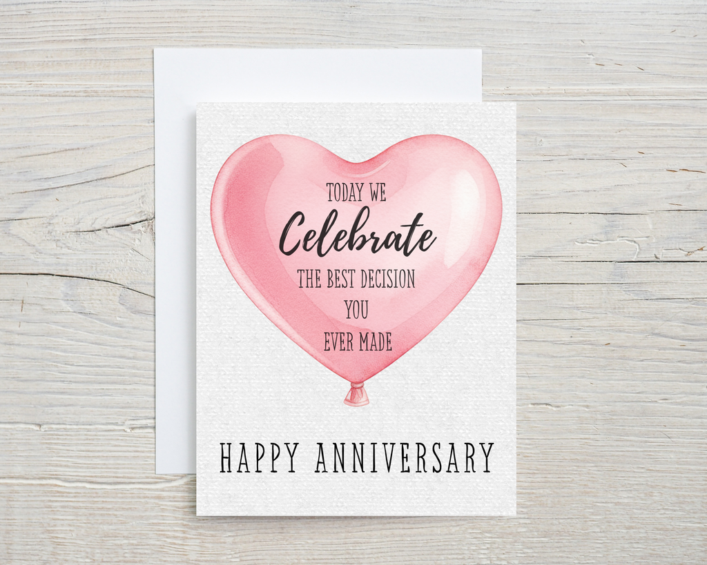 Anniversary card with pink heart balloon and text on a wooden surface