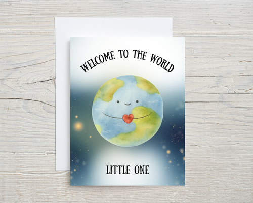 Greeting card with a cartoon Earth holding a heart, text 'Welcome to the World Little One', on a wooden surface.