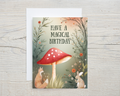 Greeting card with a red mushroom, fox, and rabbit on a wooden surface