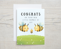 Greeting card with cartoon bees and text on a wooden surface