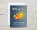 Birthday card with a cartoon fish on a blue background, featuring text 'Happy Birthday to the person who lights up the room'.