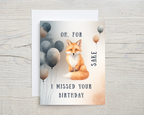 Birthday card with a fox and balloons on a wooden surface with text "Oh for fox sake I missed your birthday"