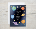 Greeting card with cartoon planets and stars on a wooden surface