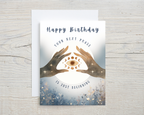 Birthday card with hands holding a moon phase design on a wooden surface 'Happy Birthday Your Next Phase Is Just Beginning'