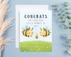 Greeting card with cartoon bees and 'Congrats on your new little bumble of joy' text on a light blue background.