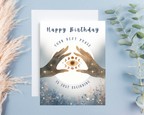 Birthday card with hands holding a moon phase design on a blue background 'Happy Birthday Your Next Phase Is Just Beginning'