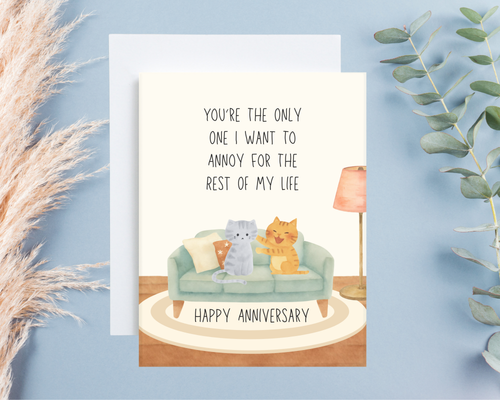Anniversary card with cats on a couch and decorative elements on a blue background