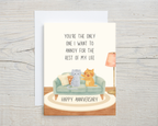 Anniversary card with two cats on a couch and text on a wooden surface