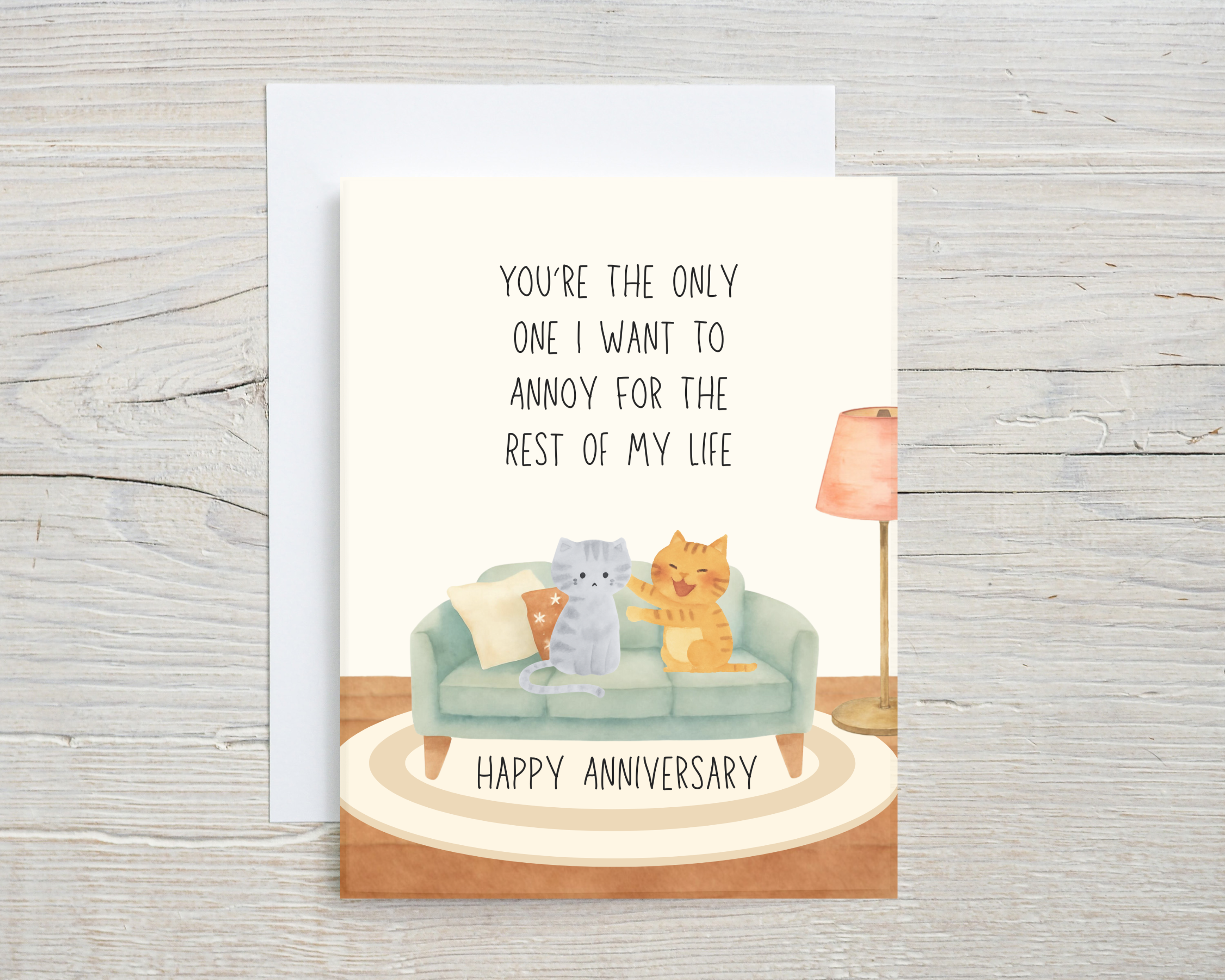 Anniversary card with two cats on a couch and text on a wooden surface