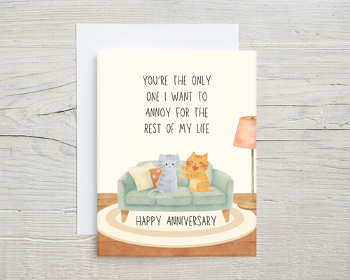 Anniversary card with two cats on a couch and text on a wooden surface